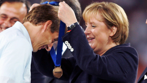 8. Juli 2006: Bundeskanzlerin Angela Merkel überreicht Bundestrainer Jürgen Klinsmann in Stuttgart die Medaille für Platz 3 bei der Heim-WM 
